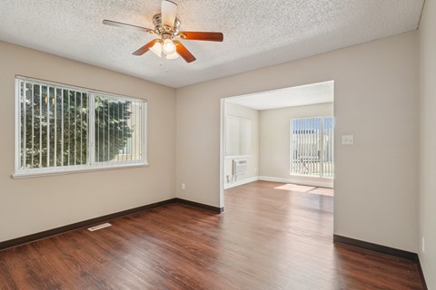 A room with a ceiling fan and wooden flooring.